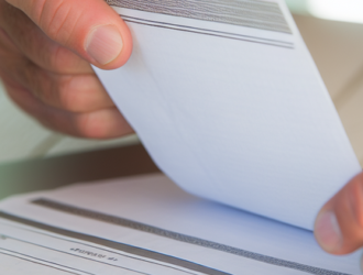 Close-up of a person analyzing a pay slip beside a laptop